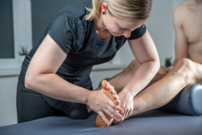 Physiotherapeutin behandelt Patient mit Fußbeschwerden