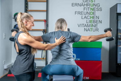 Physiotherapeutin überwacht Trainingsübung eines Patienten zur Prävention von Beschwerden